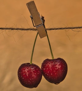 juicy cherries hanging on a line with a clothespin