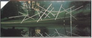 picture of tensegrity, poles held together by a wire stretched over a pond.